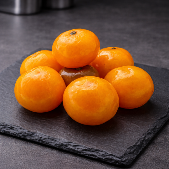 Gekonfijte Corsicaanse clementines gepresenteerd op premium leisteen, bovenaanzicht, professionele keuken