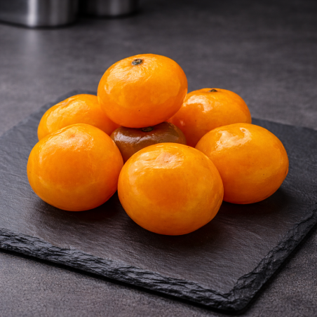 Gekonfijte Corsicaanse clementines gepresenteerd op premium leisteen, bovenaanzicht, professionele keuken