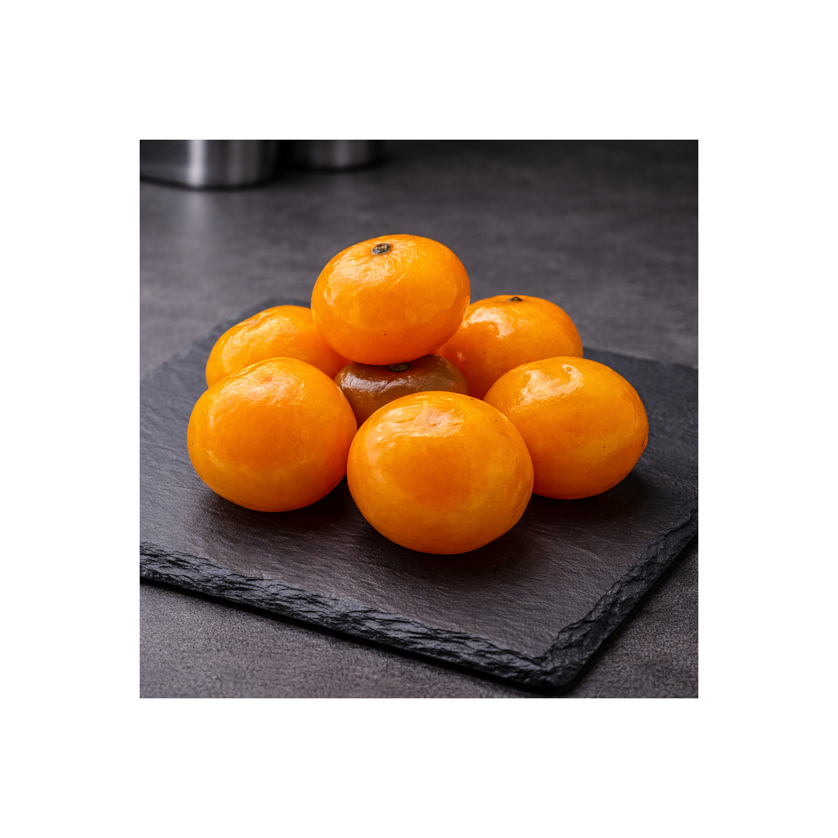 Clementinas confitadas de Córcega presentadas sobre pizarra premium, vista superior, cocina profesional