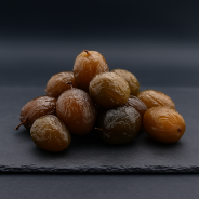 Ciruelas confitadas presentadas sobre pizarra premium en una cocina profesional