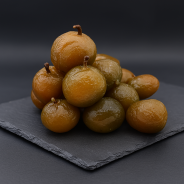 Candied plums displayed on premium slate in a professional kitchen