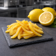 Écorces de citron confites présentées sur ardoise premium en cuisine professionnelle