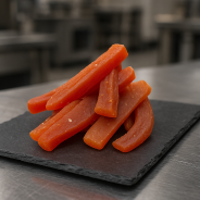 Natural candied papaya displayed on slate in a stainless-steel pro kitchen environment